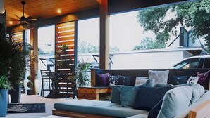 Ein moderner Außenbereich mit Holzdecke, Deckenventilator und Blick auf ein Fahrzeug im Hintergrund.