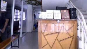 A reception area with a wooden counter, a bench, and a staircase. - Jardin Oriental Suites Ubelt Manila (Manila)