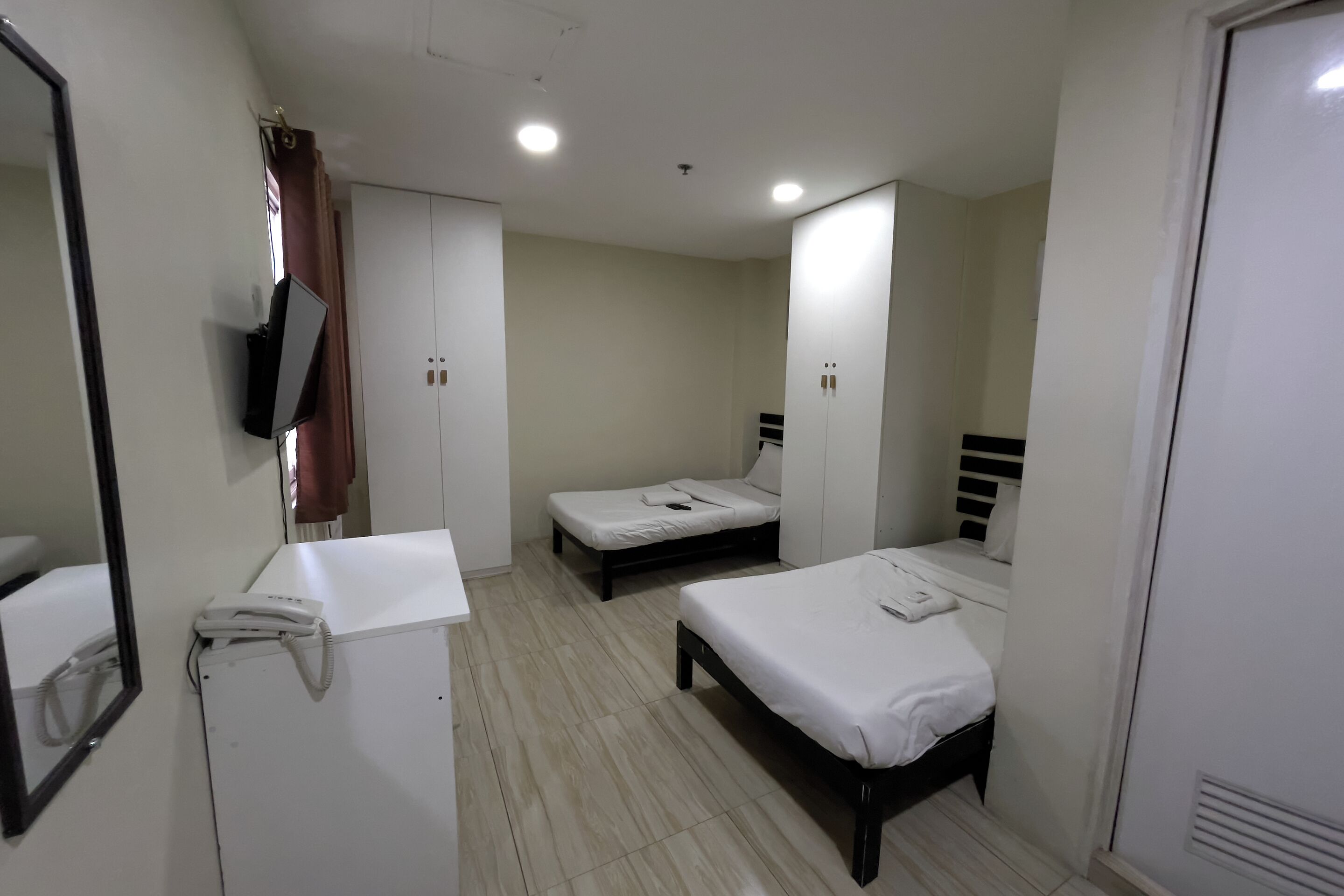 Une chambre d’hôtel comprenant un lit, une table de chevet, un miroir, une armoire et un téléphone.