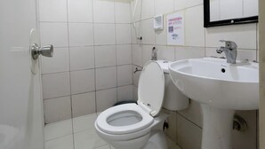 A bathroom with a white toilet, a sink, and a mirror. - Jardin Oriental Suites Ubelt Manila (Manila)