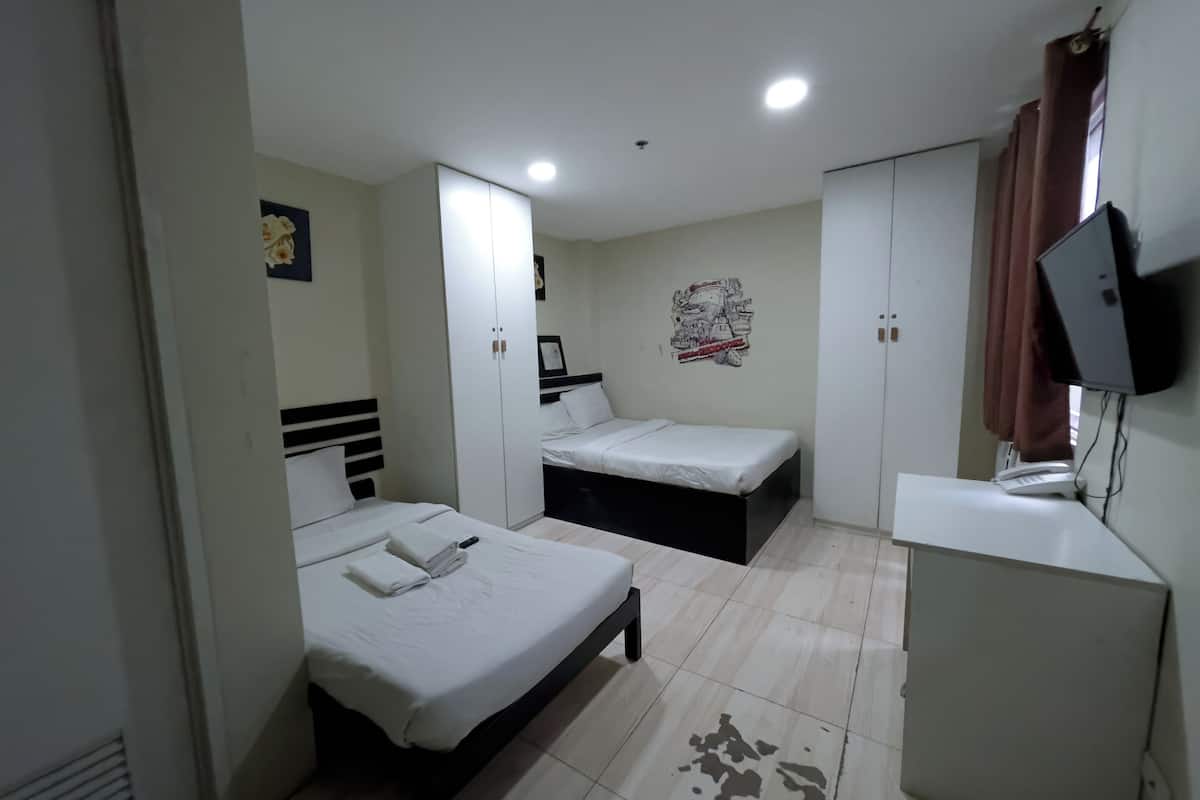 Une chambre avec deux lits, un bureau, une armoire et un téléviseur.