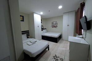 A bedroom with two beds, a desk, a wardrobe, and a television. - Jardin Oriental Suites Ubelt Manila (Manila)