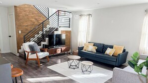 Ein modernes Wohnzimmer mit Treppe, einer Sofagarnitur und einem Fernseher.