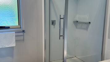 Chuveiro, toalhas de banho, sabonete, papel higiênico