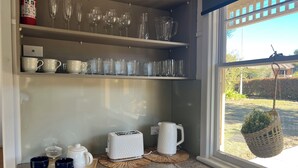 Una cucina con un piano di lavoro in marmo, un tostapane, un bollitore e diversi bicchieri su mensole.