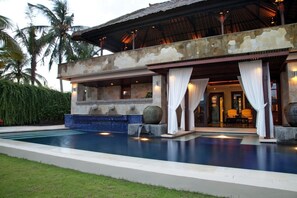 A resort with a swimming pool, a covered outdoor area, and a building with stone walls and a tiled floor. - Villa Amani (Tabanan)