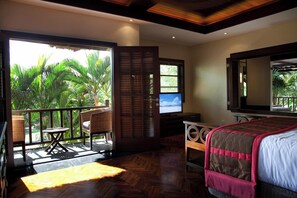 A bedroom with a balcony, wooden flooring, a bed, a TV, and a table. - Villa Amani (Tabanan)