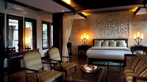 A hotel room with a large bed, two bedside tables with lamps, a sofa, and two chairs. - Villa Amani (Tabanan)