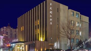 A multi-story hotel with vertical lines on the facade, illuminated windows, and a visible sign with Chinese characters.