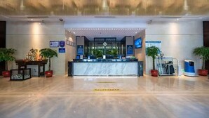A modern hotel lobby with a reception desk, digital signage, and a self-service kiosk. - Haoting International Hotel (Beijing)