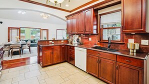 A spacious kitchen with wooden cabinets, a dishwasher, and a large window. -   Heated Pool Hot Tub PicklebalMovieTheaterPoolTable GameR Golf (Des Moines)