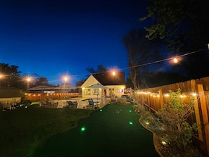 A backyard with a lawn, a small pool, and a house with a porch.