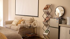 A modern living room with a sofa, a projector screen, a magazine rack, a refrigerator, and a mirror. - Xi'an Hills Lostwine Boutique Retreat (Xi'an)