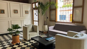 Una sala de estar con piso a cuadros, un sofá, un sillón, una mesa de centro y una planta en maceta.