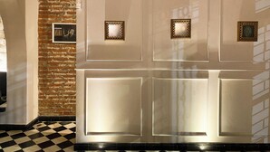Una habitación con pared de ladrillo, una puerta blanca de tres paneles y un suelo a cuadros blanco y negro.