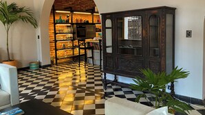 Un suelo a cuadros, un armario negro y un sofá blanco en una habitación con pared de ladrillo y un arco de entrada.
