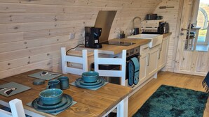 Una cocina acogedora y funcional con paredes de madera y un comedor con mesa de madera y sillas blancas.