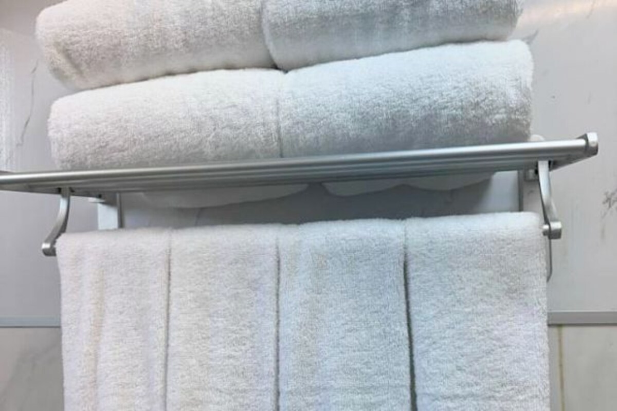 A stack of white towels on a metal rack in a bathroom.