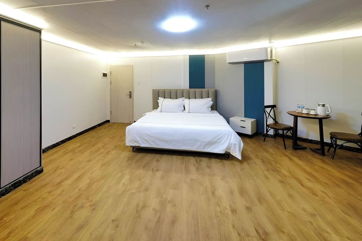 A hotel room with a large bed, bedside tables, a small table with chairs, and a ceiling light.