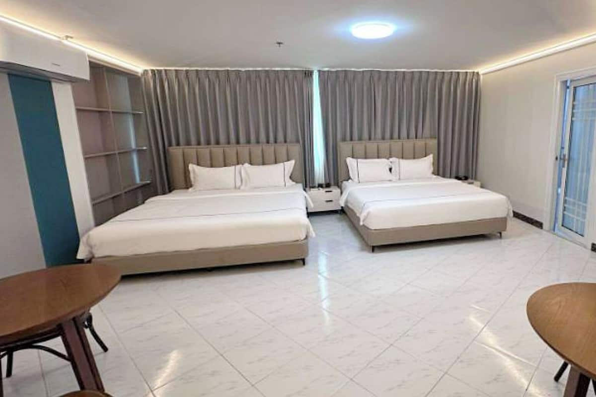 A hotel room with two beds, a desk, and a chair.