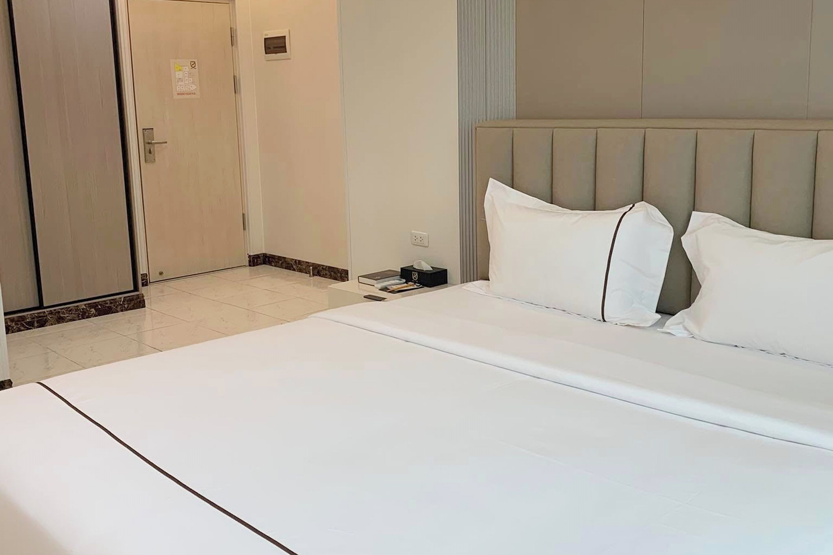 A hotel room with a large bed, a nightstand, and a door.