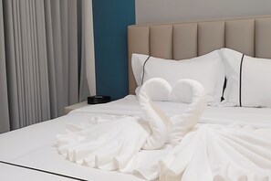 A neatly made bed with a white bedspread and pillows, a headboard, and a nightstand with a black object on it. - Aku Inn Cebu City (Cebu City)