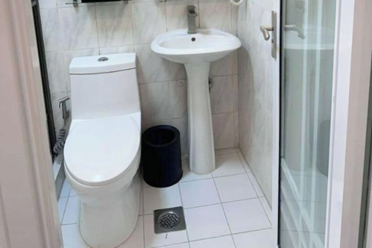 A small bathroom with a toilet, sink, and a trash bin.