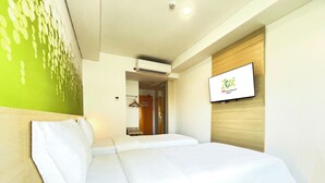 A hotel room with a bed, a TV mounted on the wall, and a door leading to a bathroom. - Zest Ambon by Swiss-Belhotel International (Ambon)
