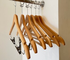 Un porte-manteau en bois, doté de plusieurs crochets, est adossé à un mur blanc.