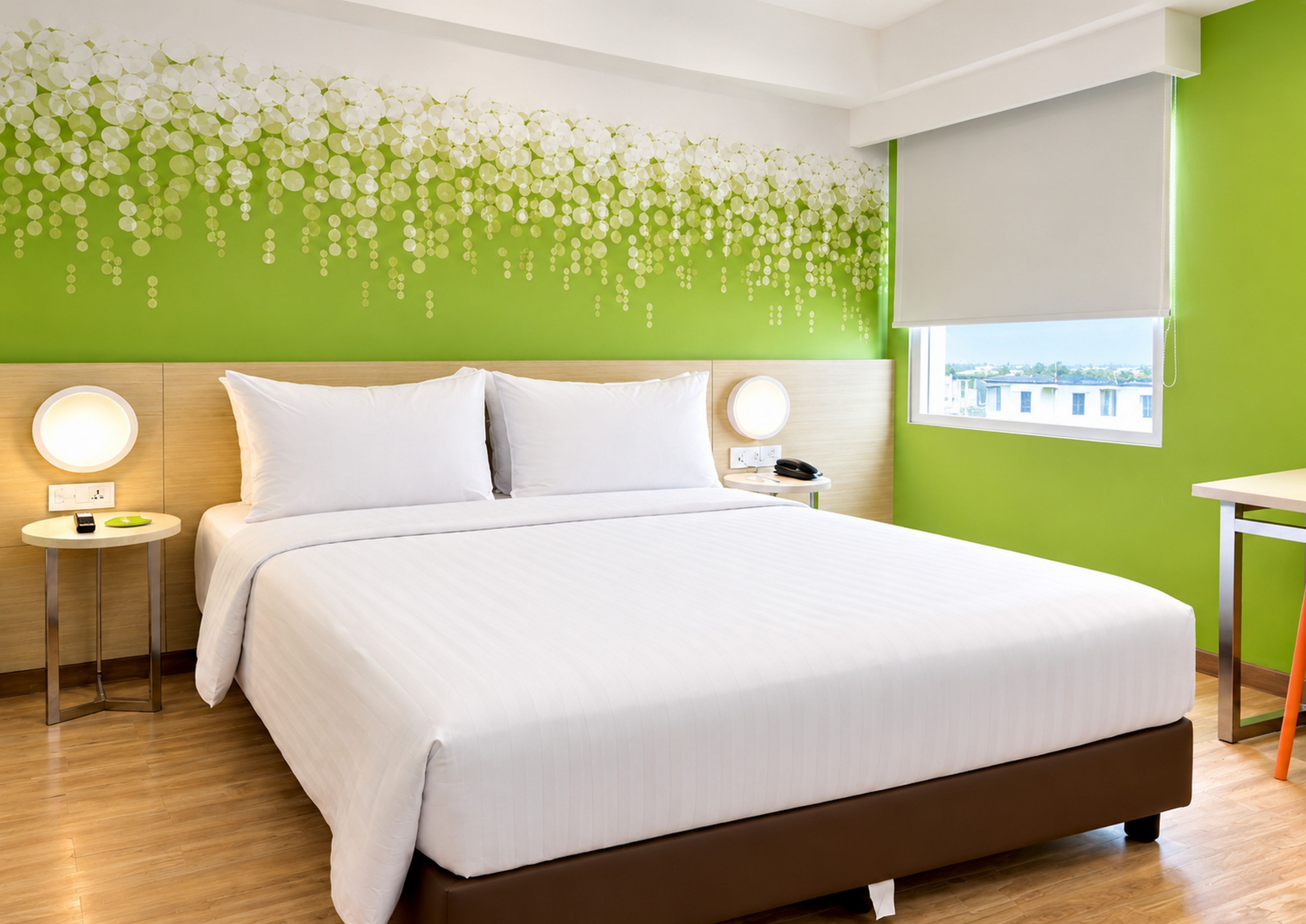 A hotel room with a bed, bedside tables, a wall-mounted light fixture, and a window with a view.