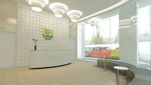 A hotel reception area with a modern design, featuring a reception desk, seating area, and large windows offering a view of the street. - Zest Ambon by Swiss-Belhotel International (Ambon)