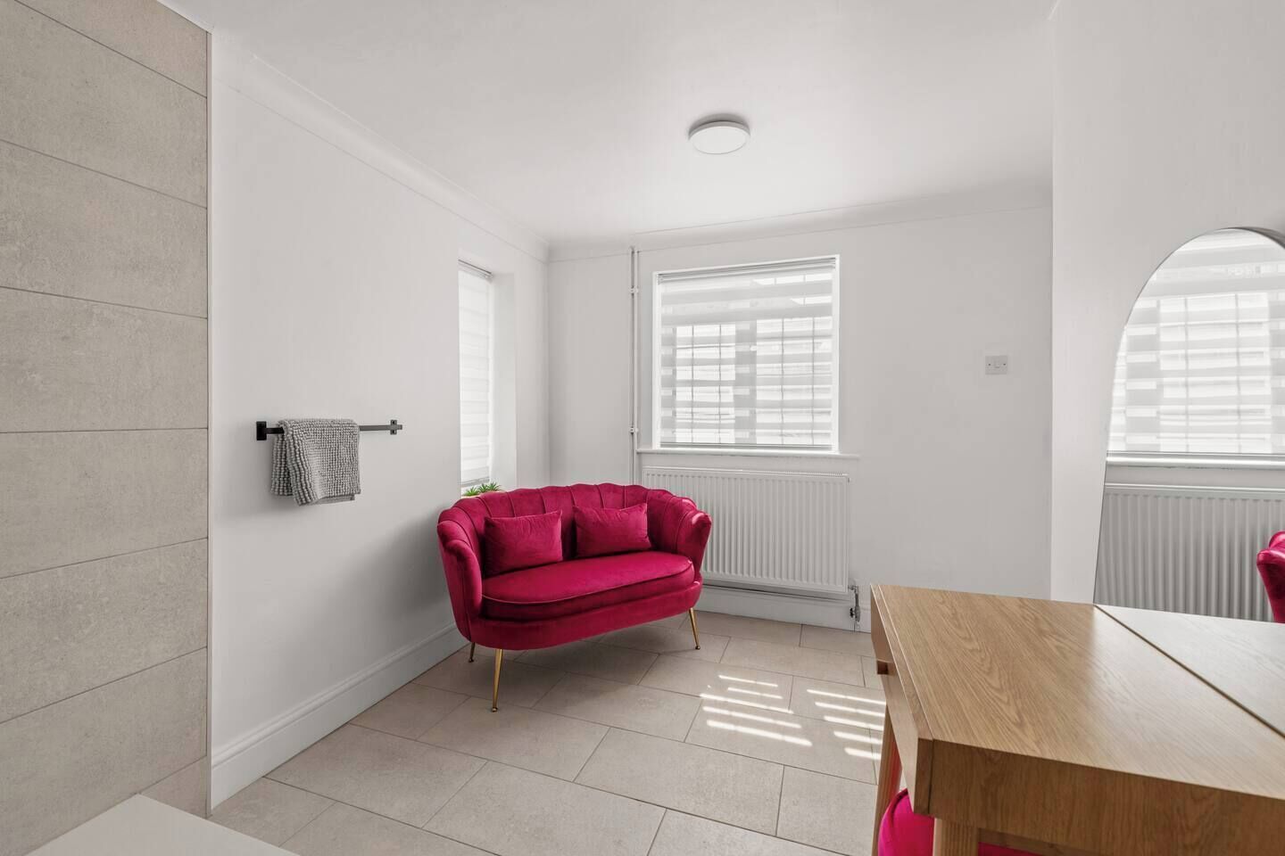 A modern, well-lit room with a red sofa, a wooden table, and a window with blinds.