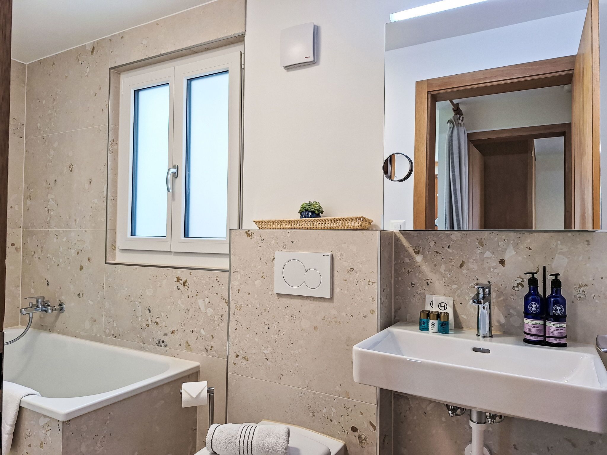 Ein Badezimmer mit Badewanne, Waschbecken, Fenster und Spiegel.