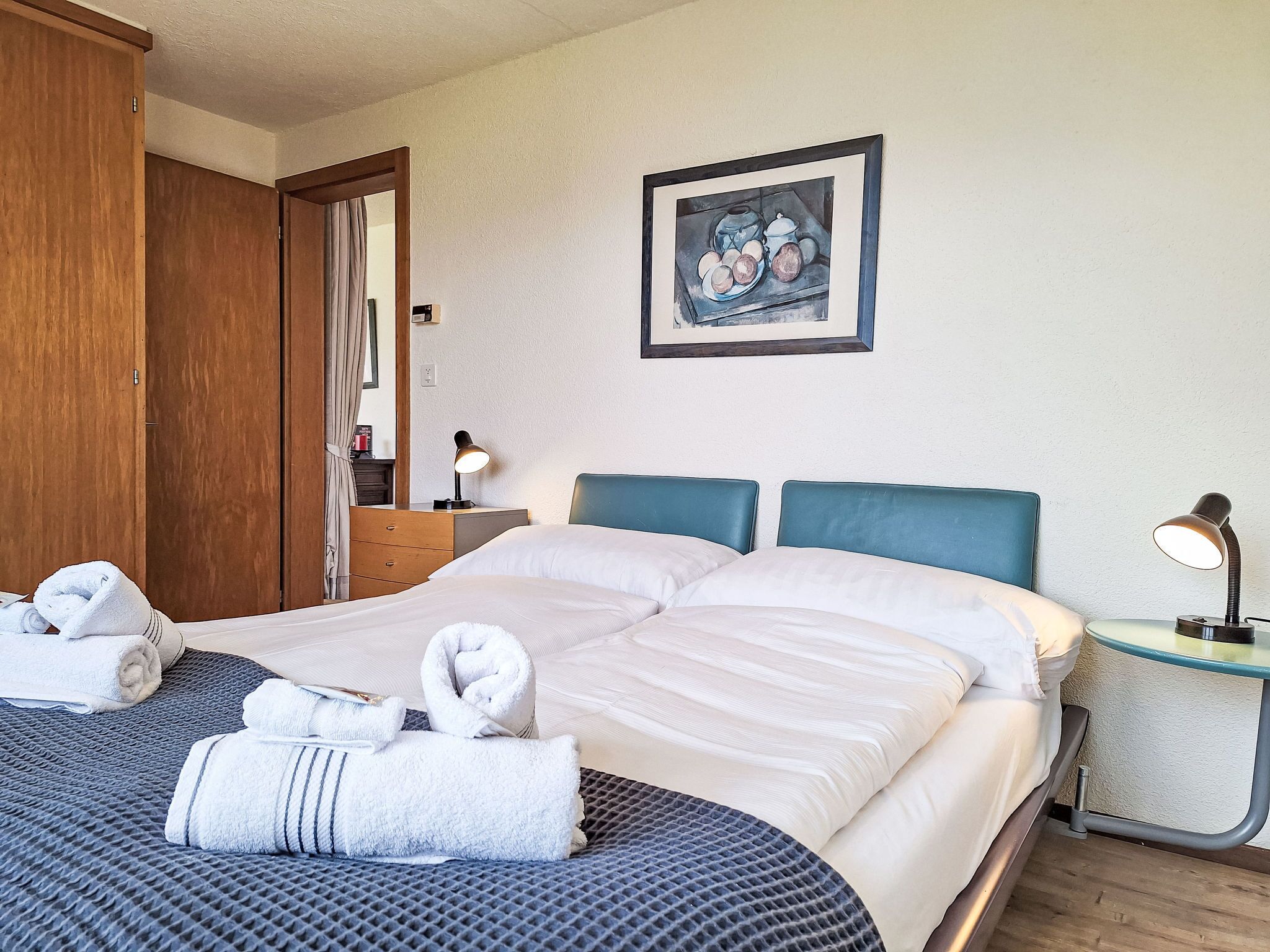 Ein Hotelzimmer mit einem großen Bett, zwei Nachttischen mit Lampen, einem Holzschrank und einem gerahmten Kunstwerk an der Wand.