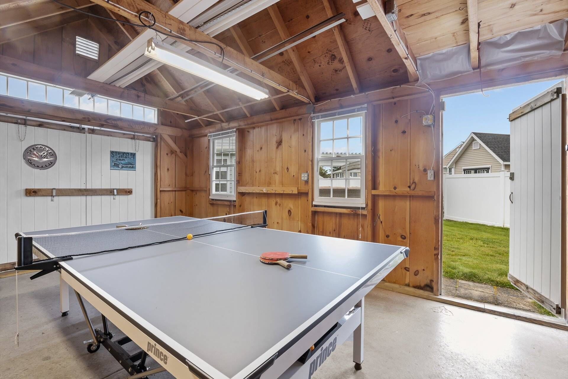 Una mesa de ping pong en una habitación con paredes de madera y ventanas amplias.