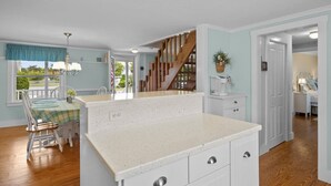 A kitchen with a white countertop, wooden floor, and a view of the outdoors through a window. - Perfect vacation home : Cape Cod Charm & Comfort. Walk to private beach (Bourne)