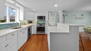 A modern kitchen with white cabinets, a stainless steel sink, and a wooden floor. - Perfect vacation home : Cape Cod Charm & Comfort. Walk to private beach (Bourne)