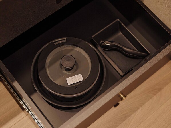 A drawer with a black circular object, a small rectangular item, and a metallic tool. - illi Tria Shibuya (Tokyo)