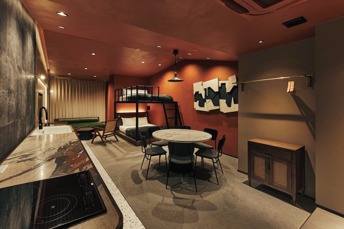 A modern interior with a bunk bed, round dining table, and a kitchen area.