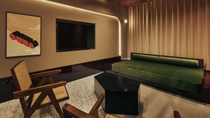 A modern hotel room with a green sofa, a flat-screen TV mounted on the wall, a wooden chair, and a small black table. - illi Tria Shibuya (Tokyo)