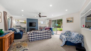 A spacious living room with a fireplace, a television, and a large window offering a view of the outdoors. - The Abbey - Point Lonsdale (Point Lonsdale)