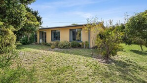 A modern two-story house with a yellow facade, large windows, and a well-maintained garden with various shrubs and a small tree. - The Abbey - Point Lonsdale (Point Lonsdale)
