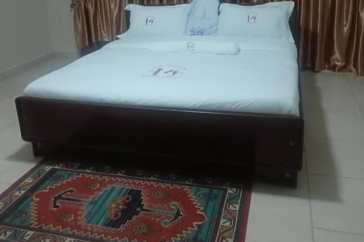 Une chambre à coucher avec un lit, du linge de lit blanc, un baldaquin et un tapis à motifs.