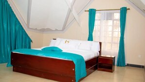 Ein Schlafzimmer mit einem Holzbett, blaue Vorhänge und einem Fenster mit weißen Vorhängen.