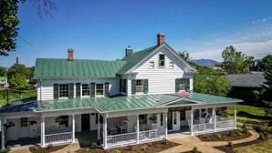 Un bâtiment blanc à deux étages, doté d’un toit végétalisé, d’un porche abrité et d’une enseigne indiquant : « The Legacy Inn ».