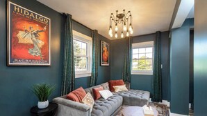 Un salon moderne avec un canapé d’angle, une table basse ronde et un lustre.