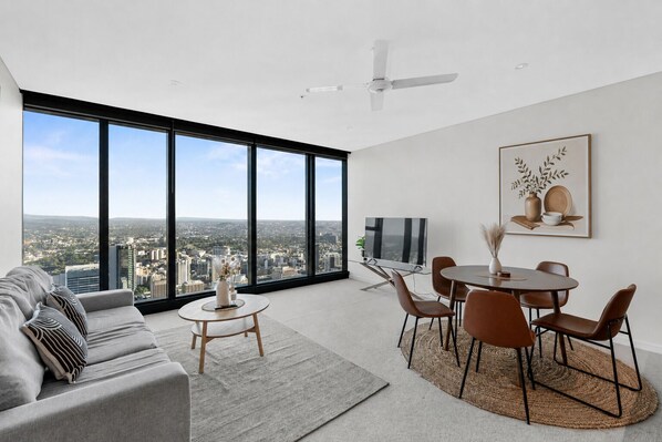 A modern living room with a city view, a dining area with chairs and a table, and a large window.