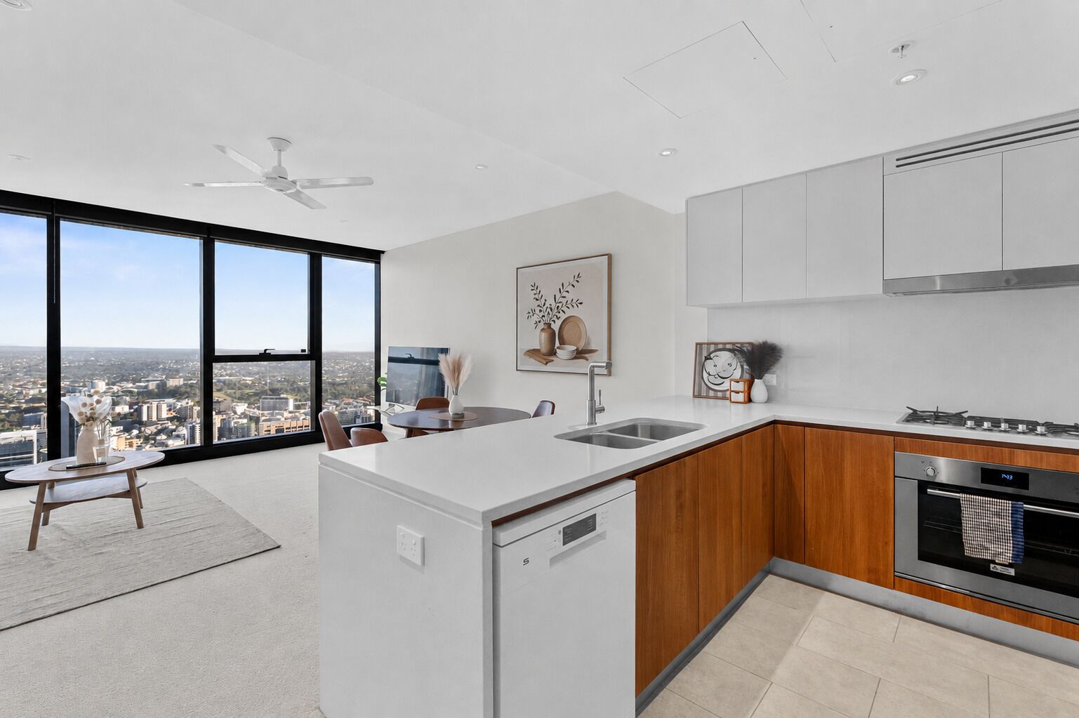 A modern kitchen with a view of the city, a dining area with a table and chairs, and a ceiling fan.