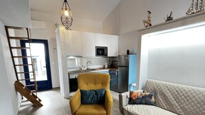 Un appartement moderne comprenant un salon, un fauteuil jaune, une table basse en bois, un canapé, un coin cuisine et un escalier.