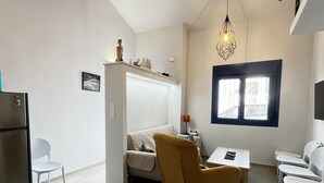 Un espace de vie compact comprenant un coin cuisine, un canapé, une table à manger et une fenêtre avec vue.